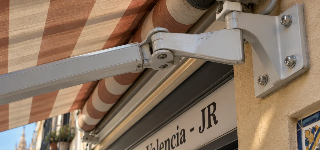 Primer plano de un toldo rayado y su soporte en una fachada de Russafa. Que opciones hay para la reparacion y mantenimiento de toldos en Valencia