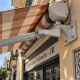 Primer plano de un toldo rayado y su soporte en una fachada de Russafa. Que opciones hay para la reparacion y mantenimiento de toldos en Valencia
