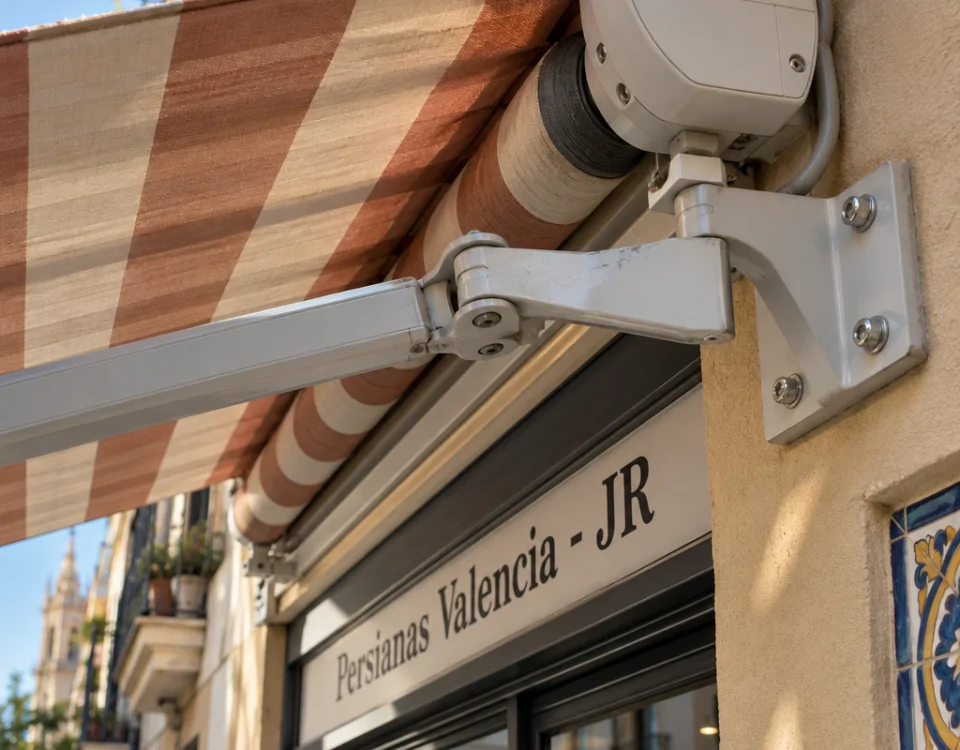 Primer plano de un toldo rayado y su soporte en una fachada de Russafa. Que opciones hay para la reparacion y mantenimiento de toldos en Valencia